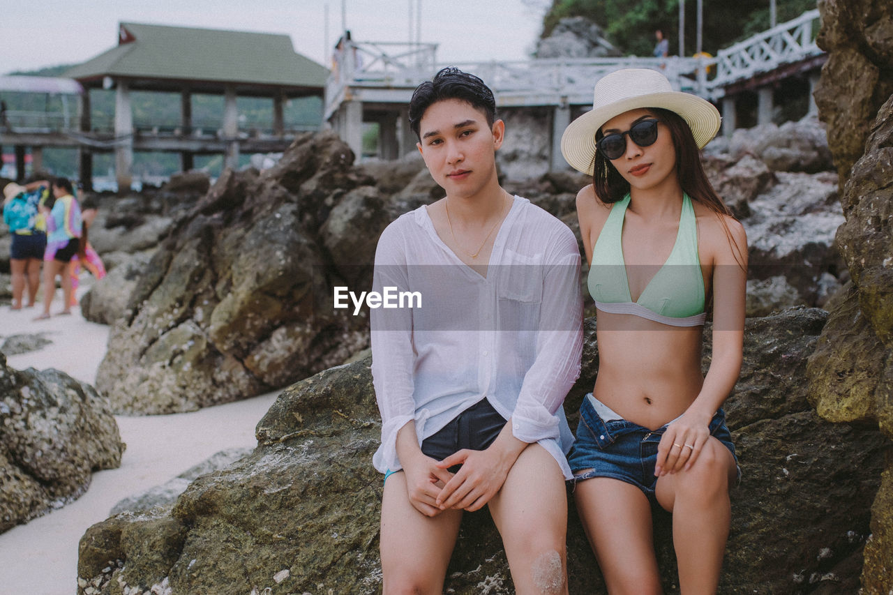 Portrait of couple sitting on rock at beach