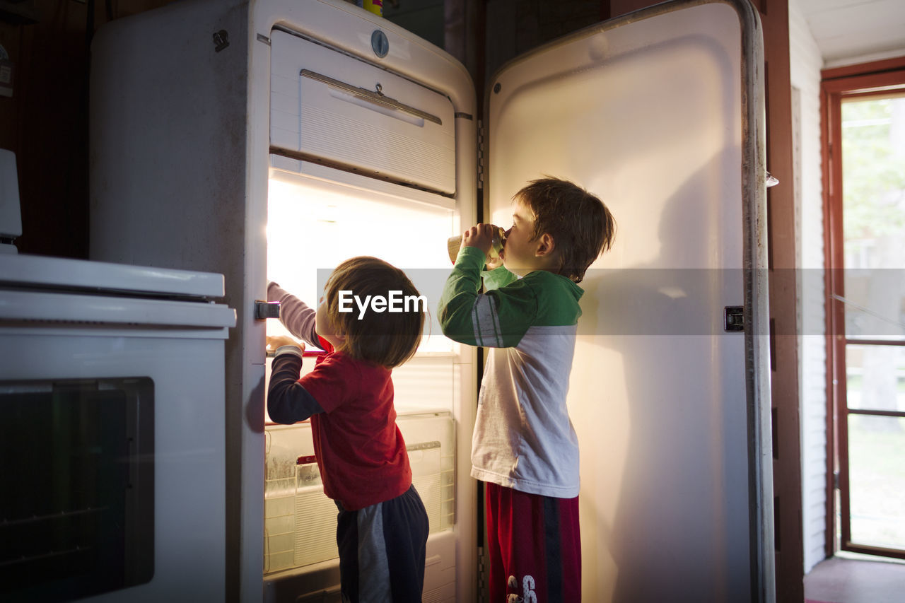 Boys taking food from fridge