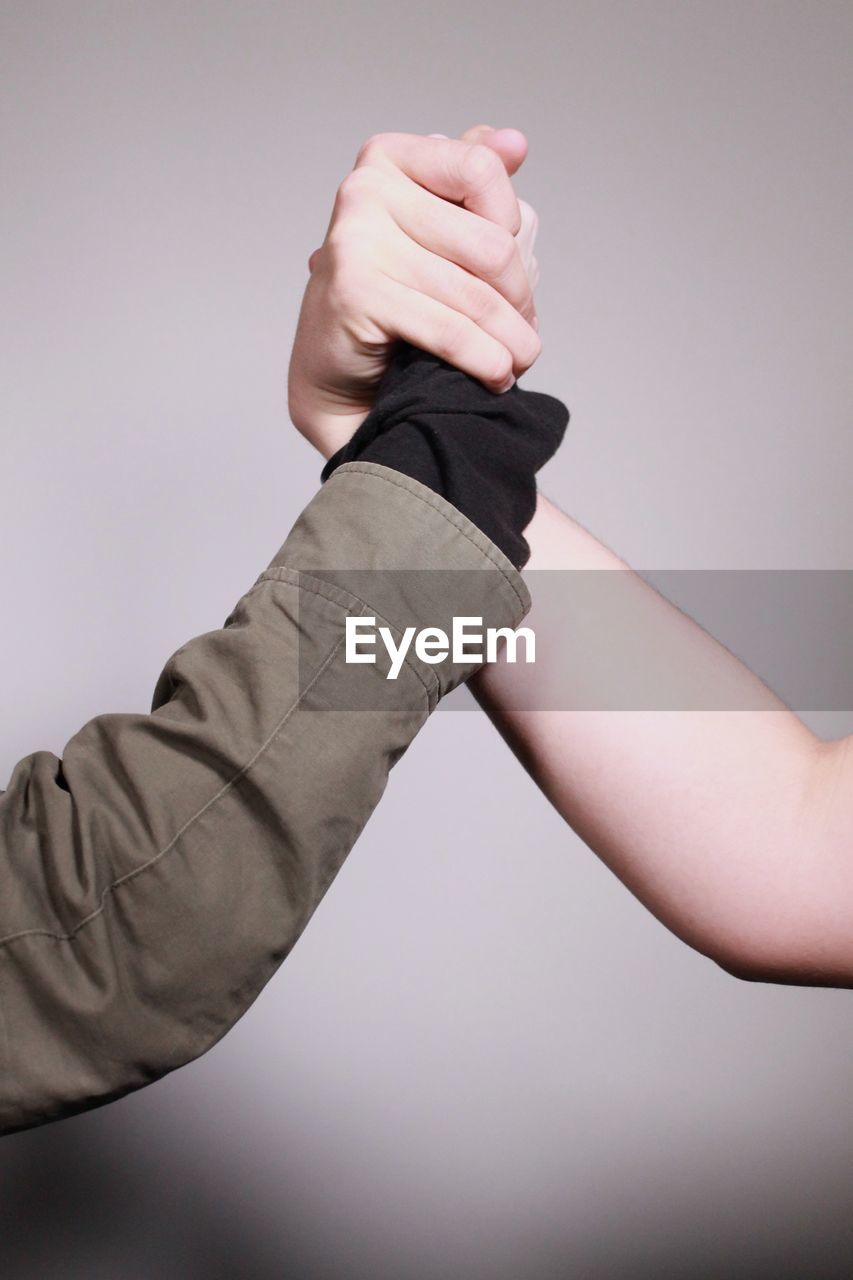 Cropped image of people holding hands against white background