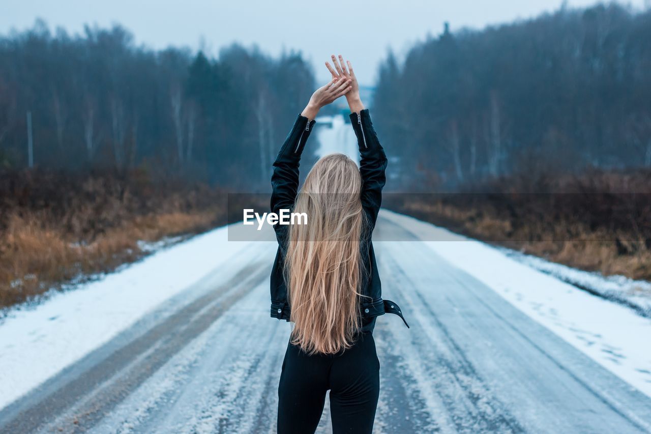 Rear view of woman standing on snow covered road