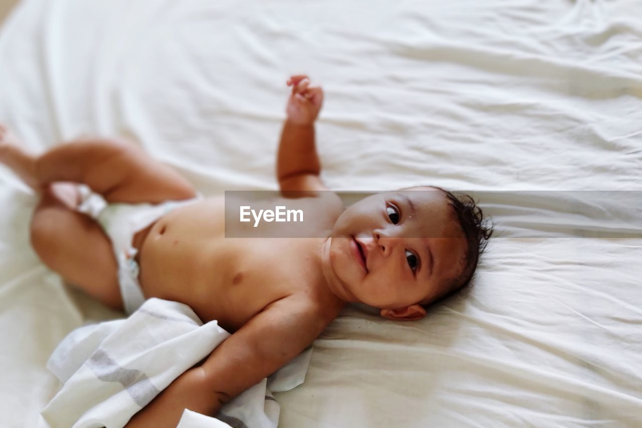 High angle view of baby boy lying on bed at home