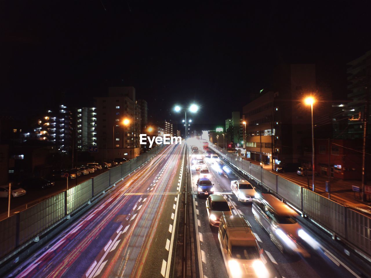 Vehicles on road along built structures at night