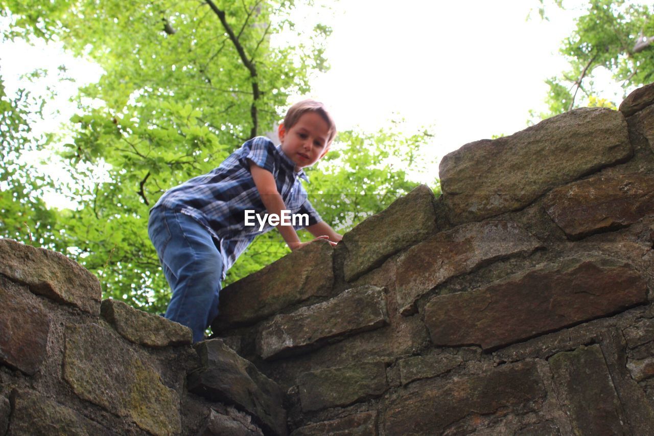 PORTRAIT OF HAPPY BOY STANDING ON ROCK