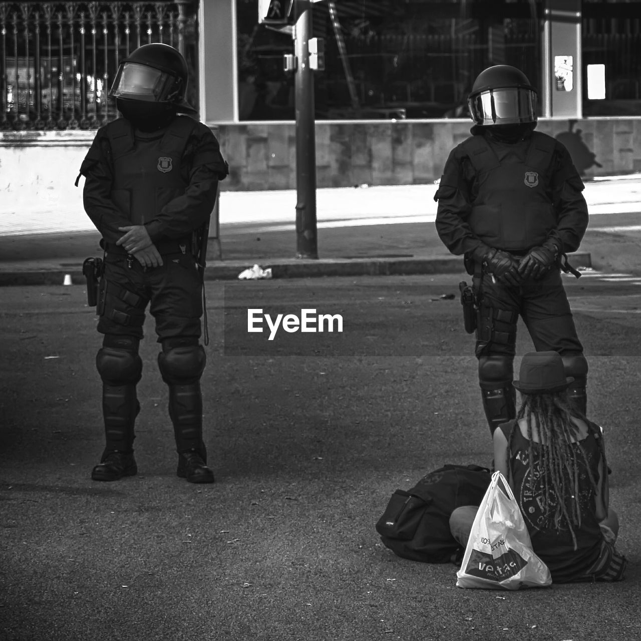 Police men standing by homeless female hipster on road in city