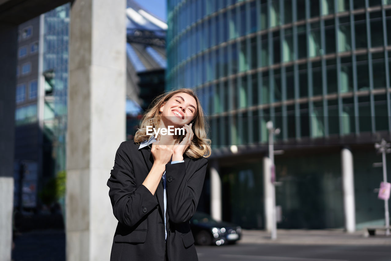 businesswoman talking on mobile phone while standing in city