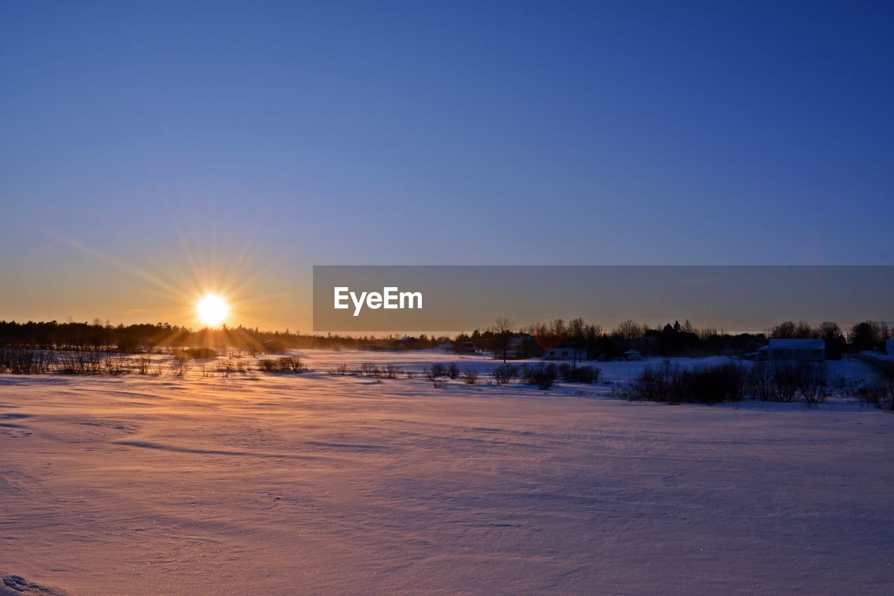 Scenic view of frozen landscape against clear sky during winter