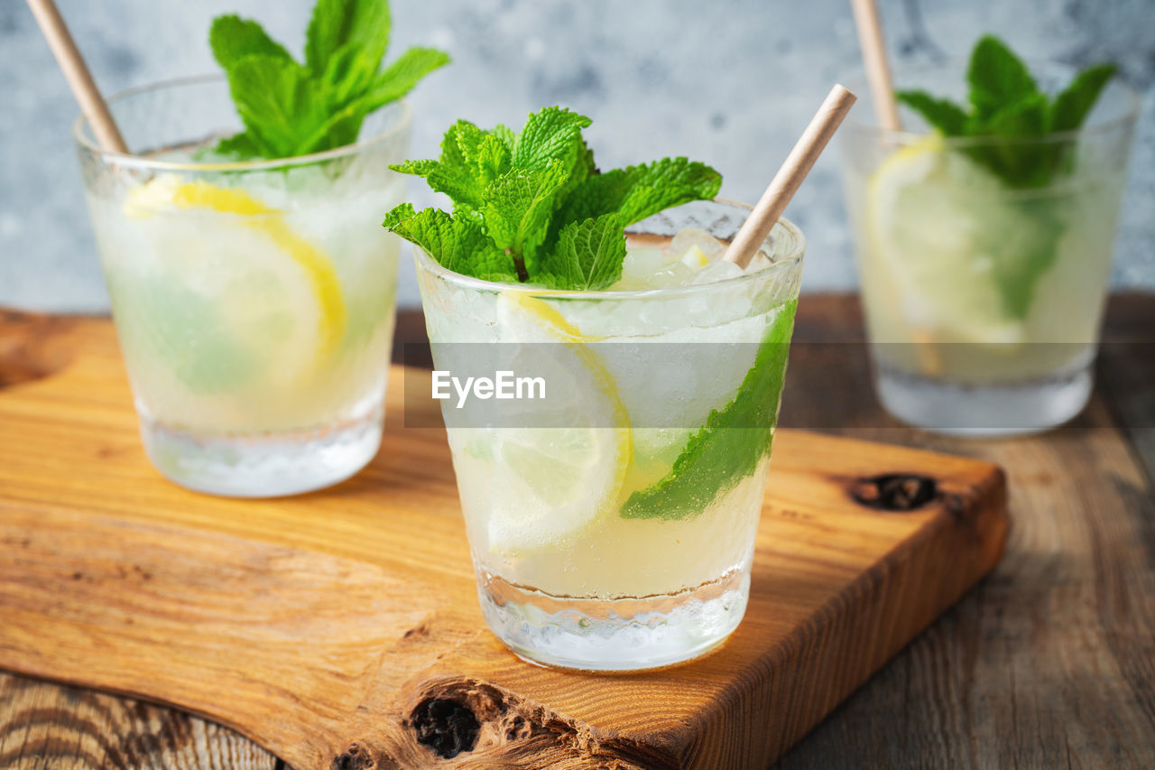 Two glass with lemonade or mojito cocktail with lemon and mint, cold refreshing drink.