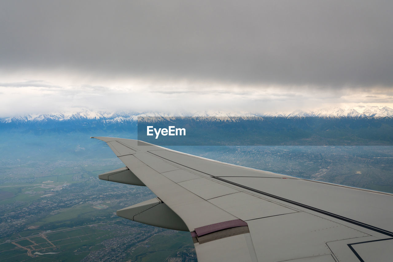 AIRPLANE FLYING IN SKY OVER MOUNTAINS