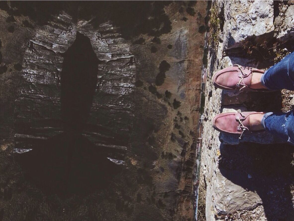 Tilt image of person standing at edge of rock