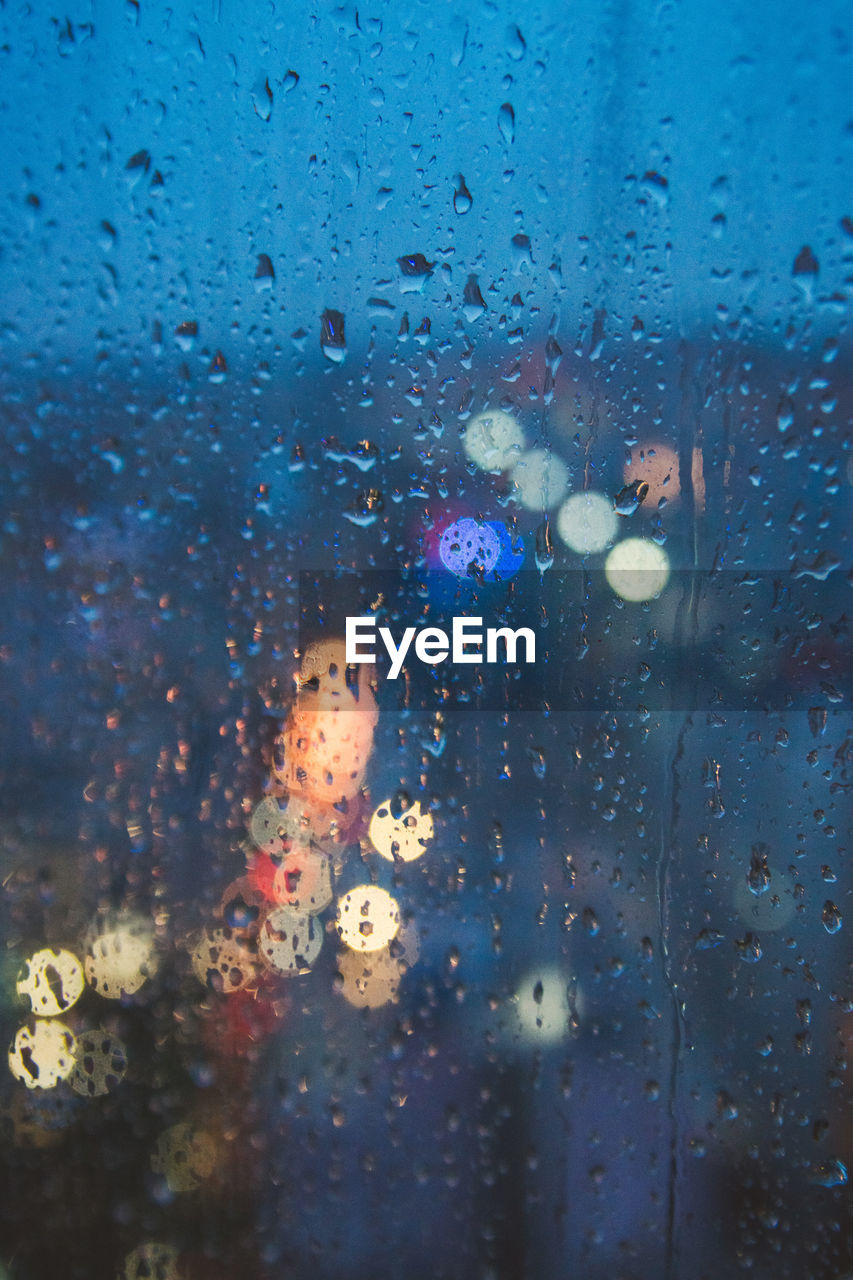 Full frame shot of wet window in rainy season with bokeh lights