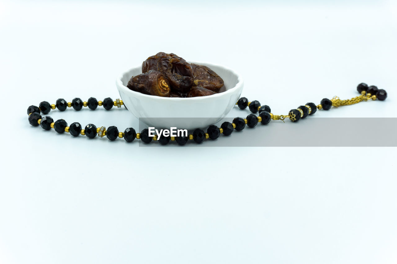 Dates and rosary over white background
