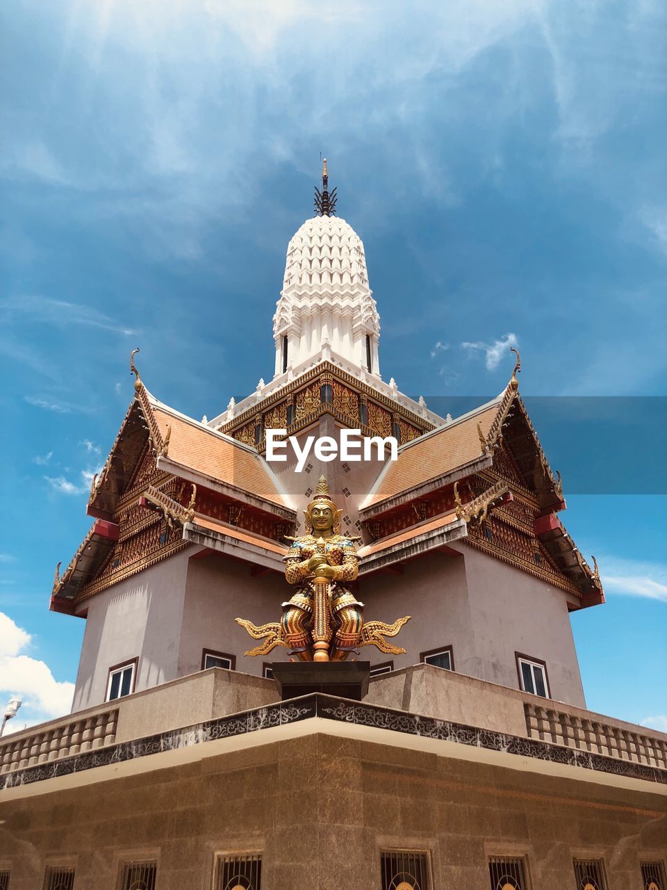 Low angle view of statue by temple against sky