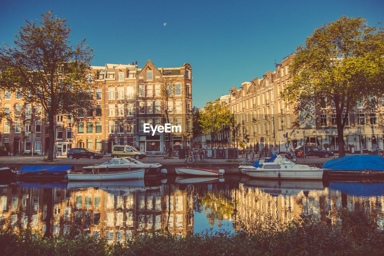 BOATS IN RIVER WITH BUILDINGS IN BACKGROUND