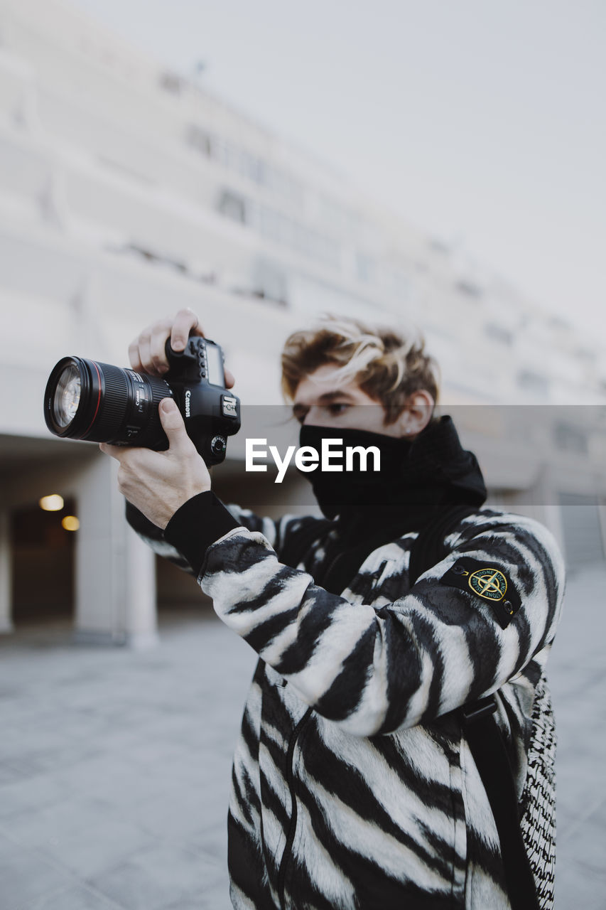 MIDSECTION OF WOMAN PHOTOGRAPHING WITH CAMERA ON SNOW