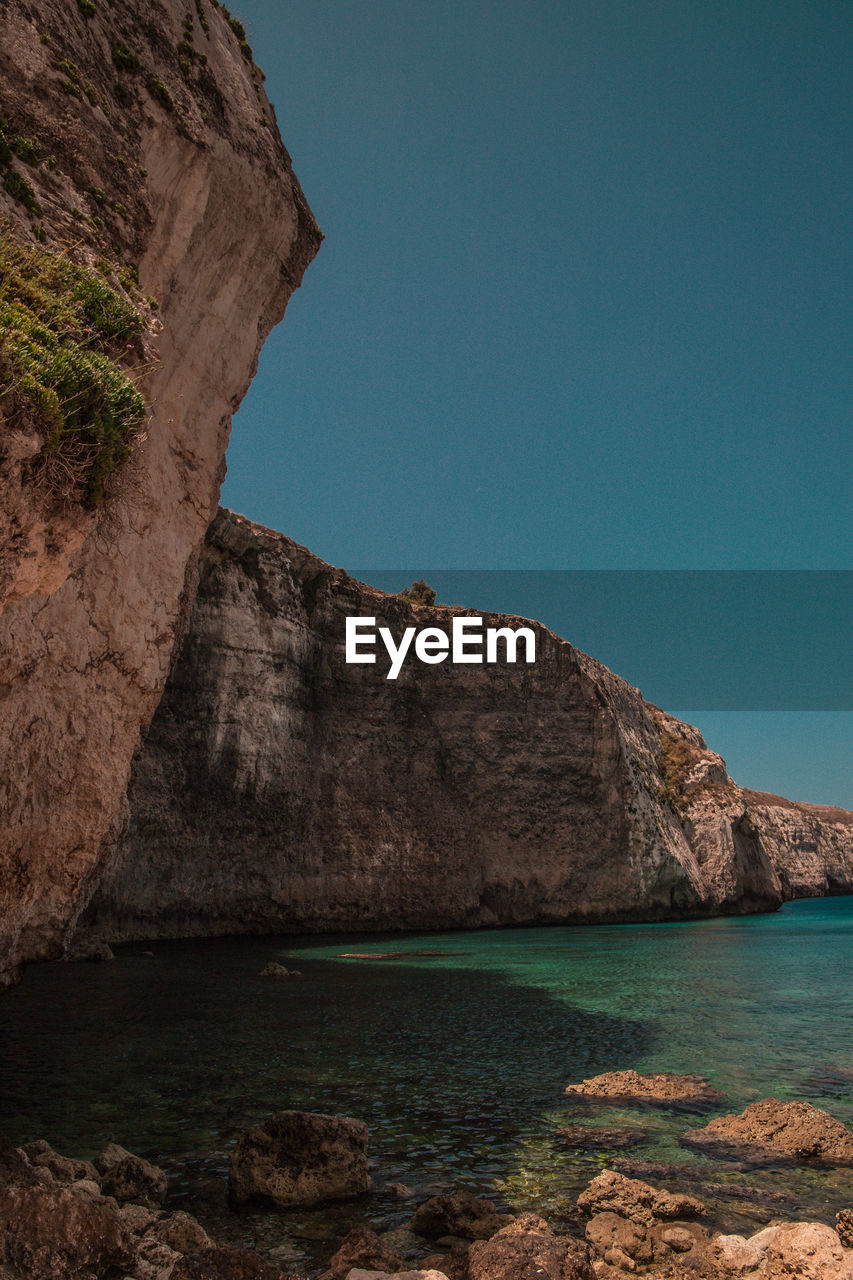 Scenic view of sea and mountains against clear sky