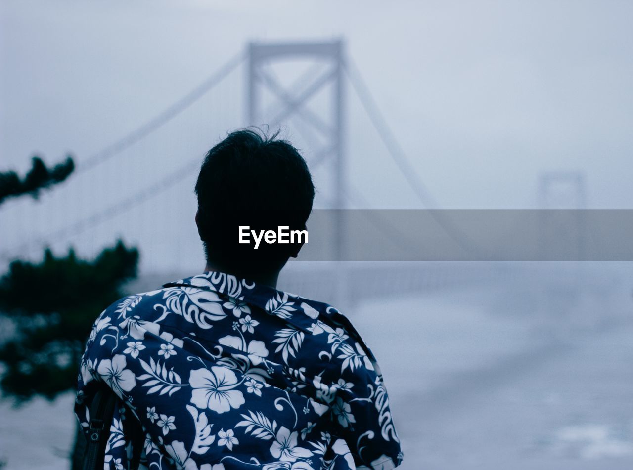 Rear view of man looking at suspension bridge