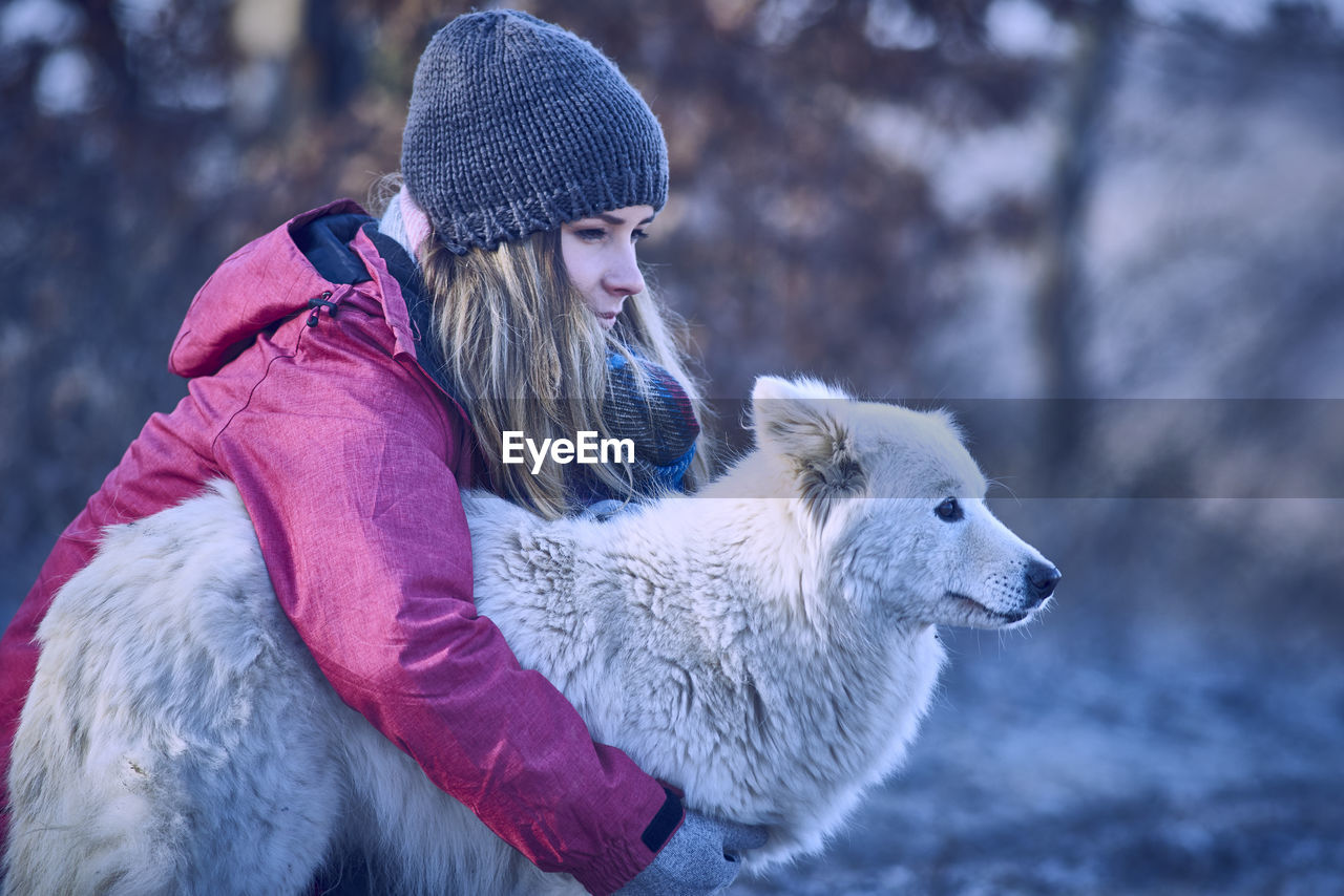 Woman embracing dog during winter