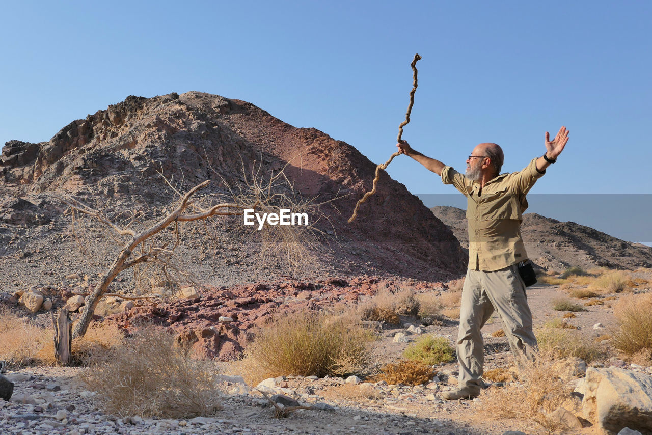 Senior man standing on rock against sky in the desert 