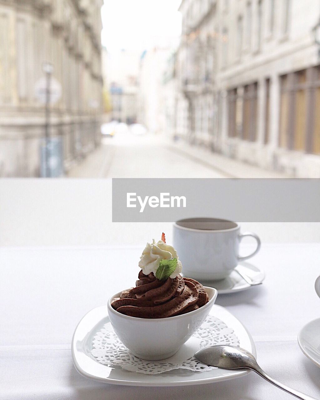 Close-up of coffee with dessert served on table by window