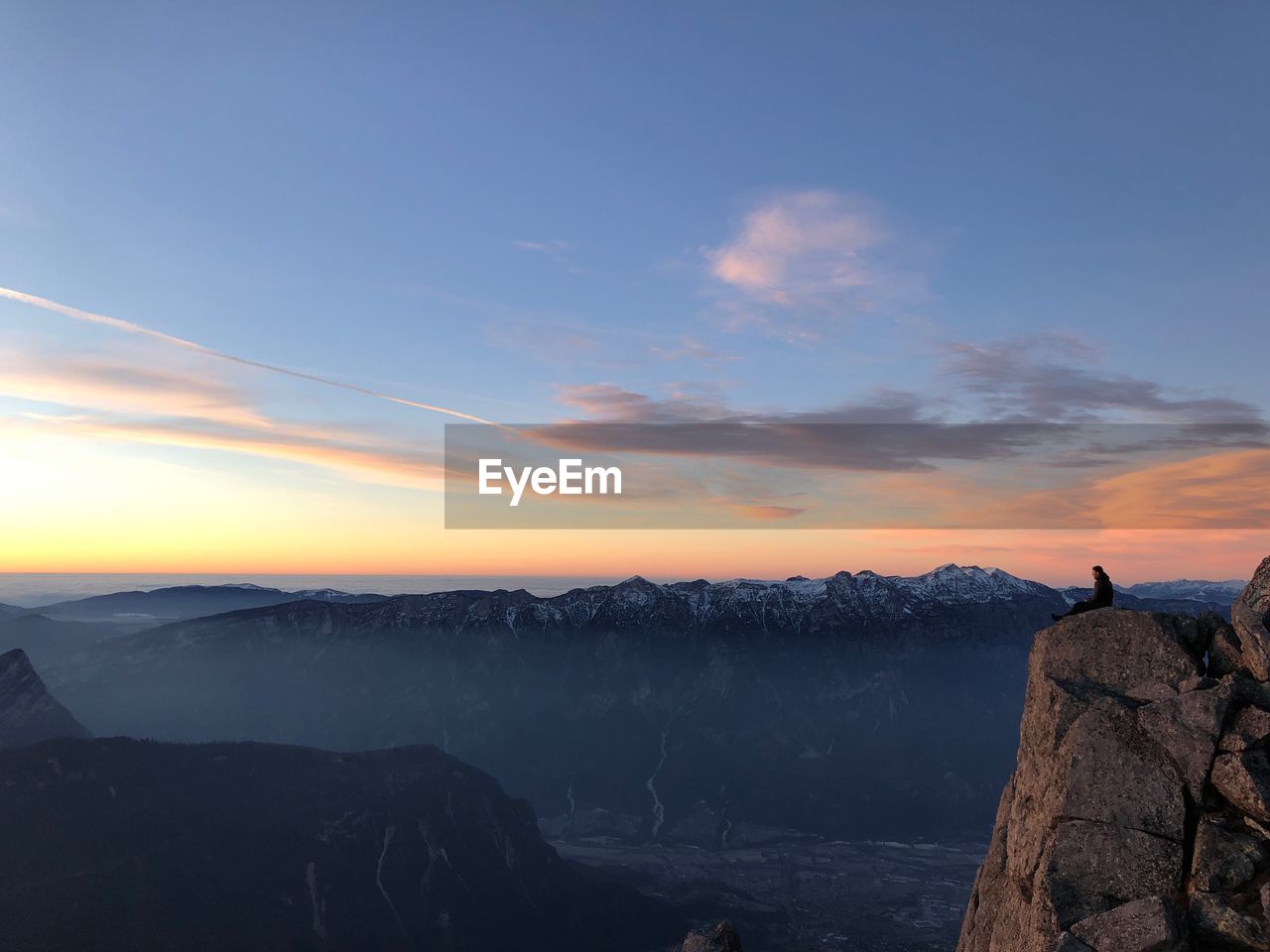 MAN LOOKING AT VIEW OF ROCK AGAINST SKY DURING SUNSET