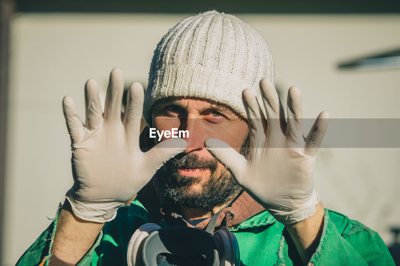 Portrait of man wearing gloves gesturing outdoors
