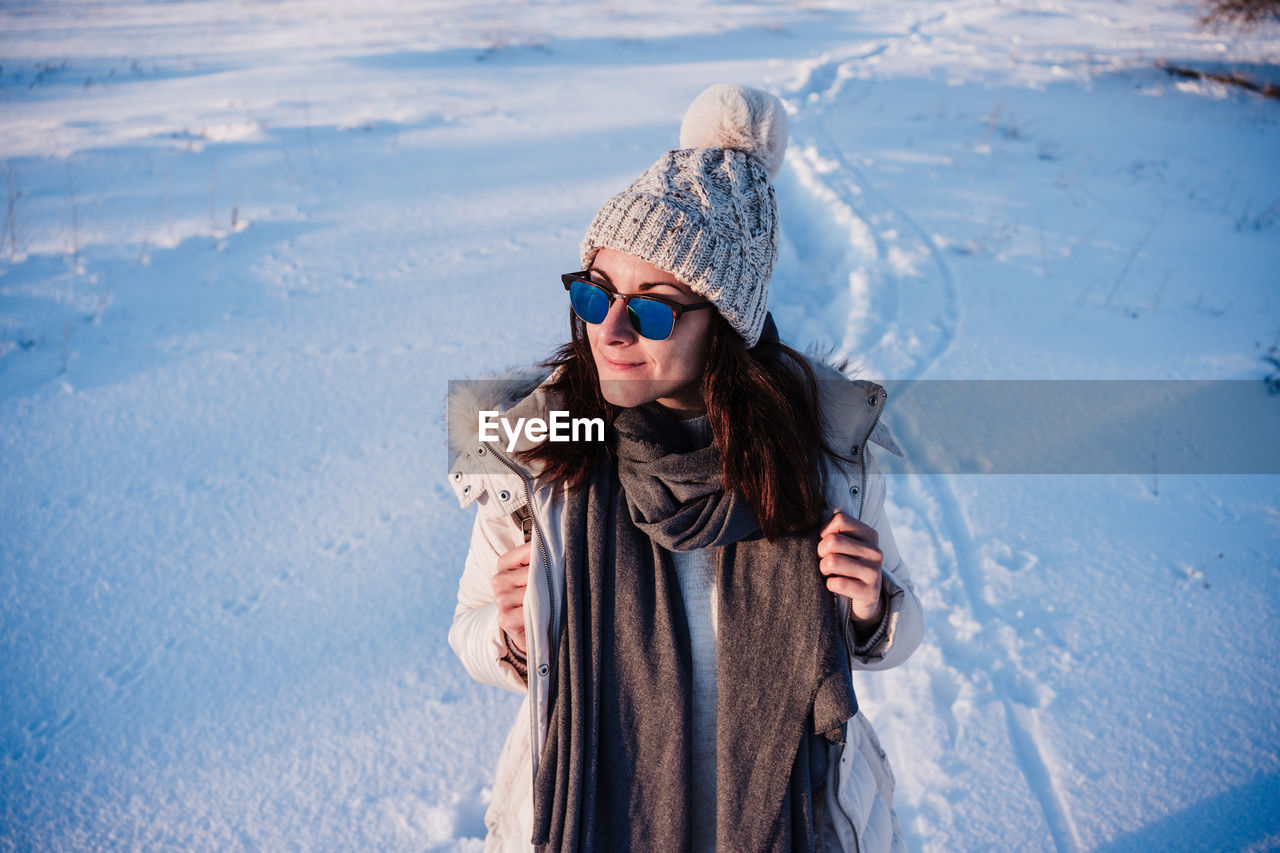 Happy young woman hiking in snowy mountain wearing modern coat at sunset. winter season. nature