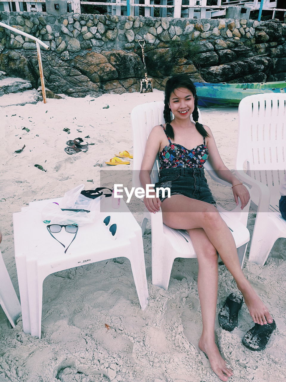 Portrait of woman sitting on chair at beach