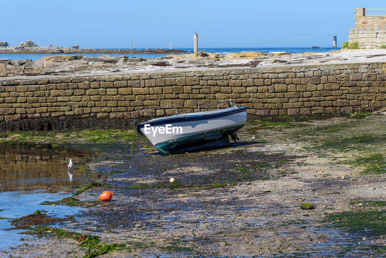 Boat moored on shore against wall