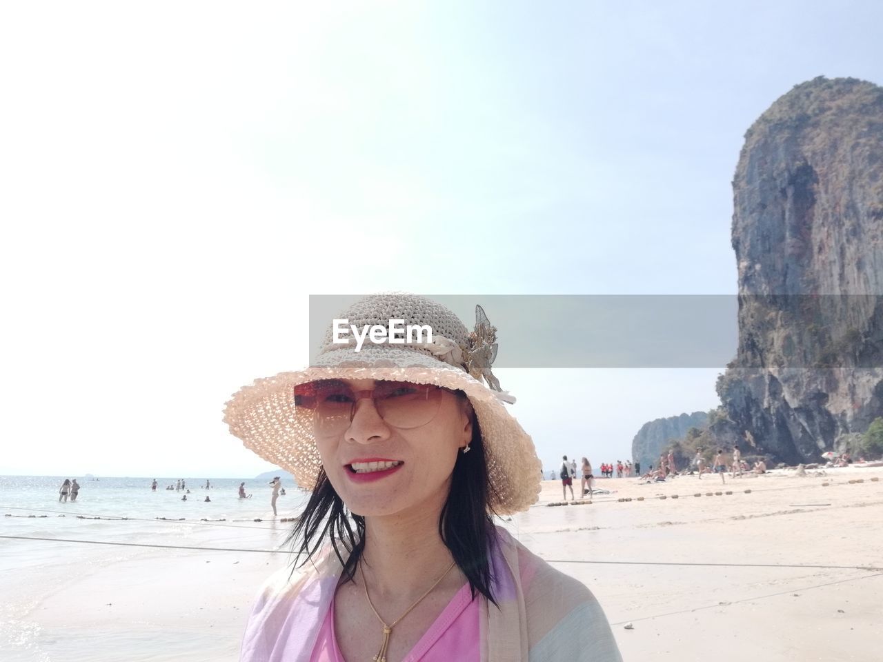 Portrait of woman wearing hat standing at beach