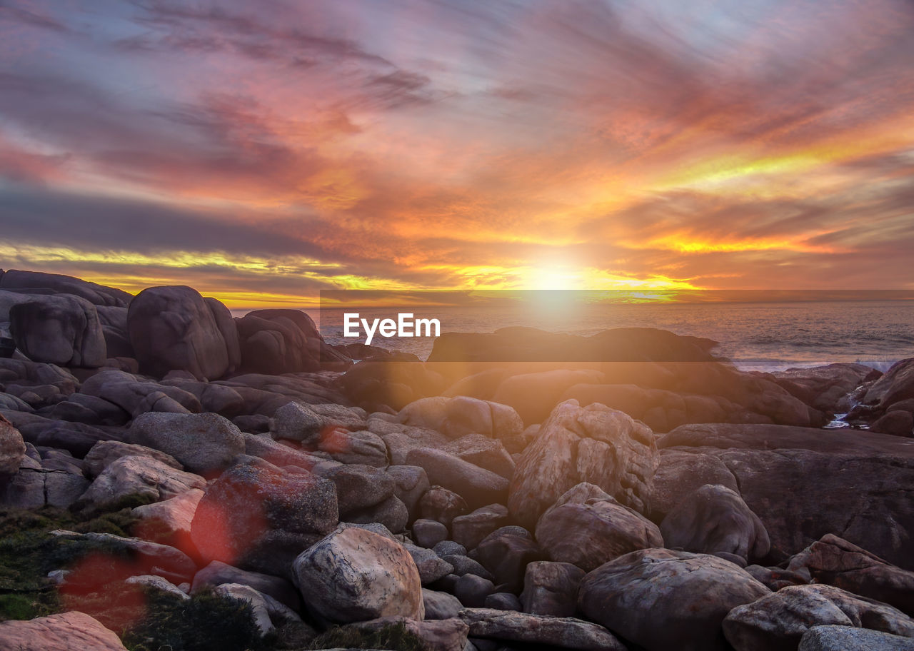 ROCKS IN SEA AGAINST SUNSET SKY