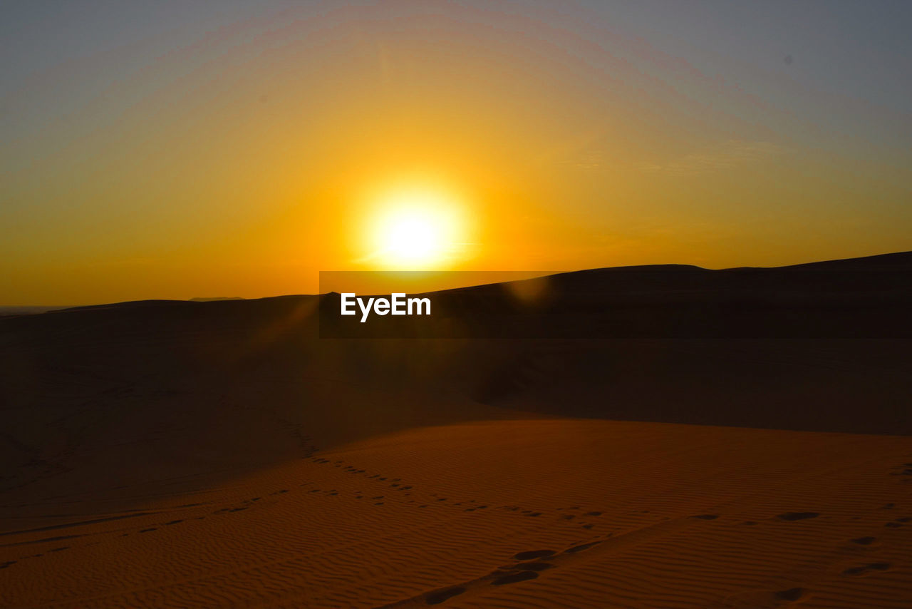 Scenic view of desert against sky during sunset