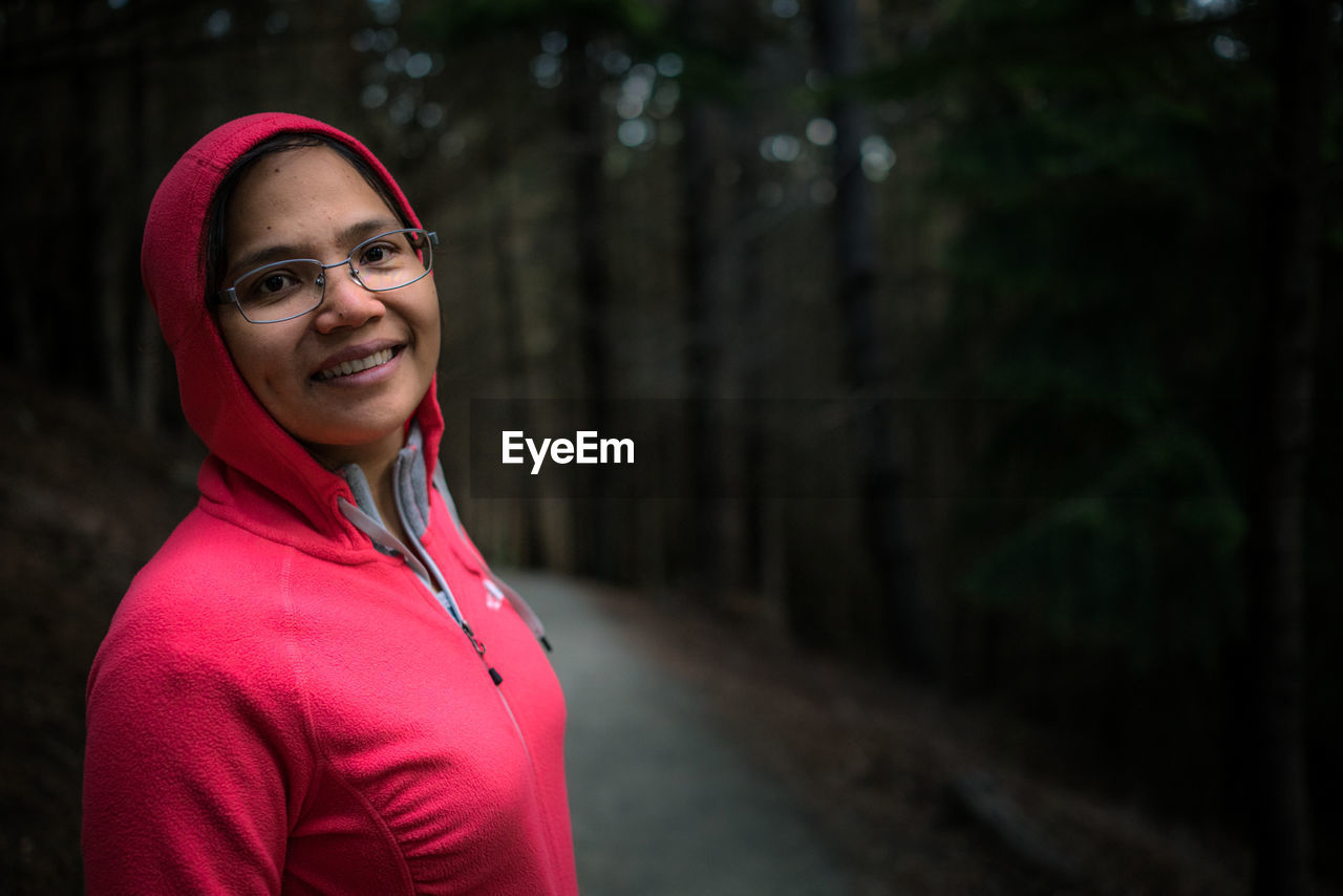 Portrait of young woman standing on footpath in forest