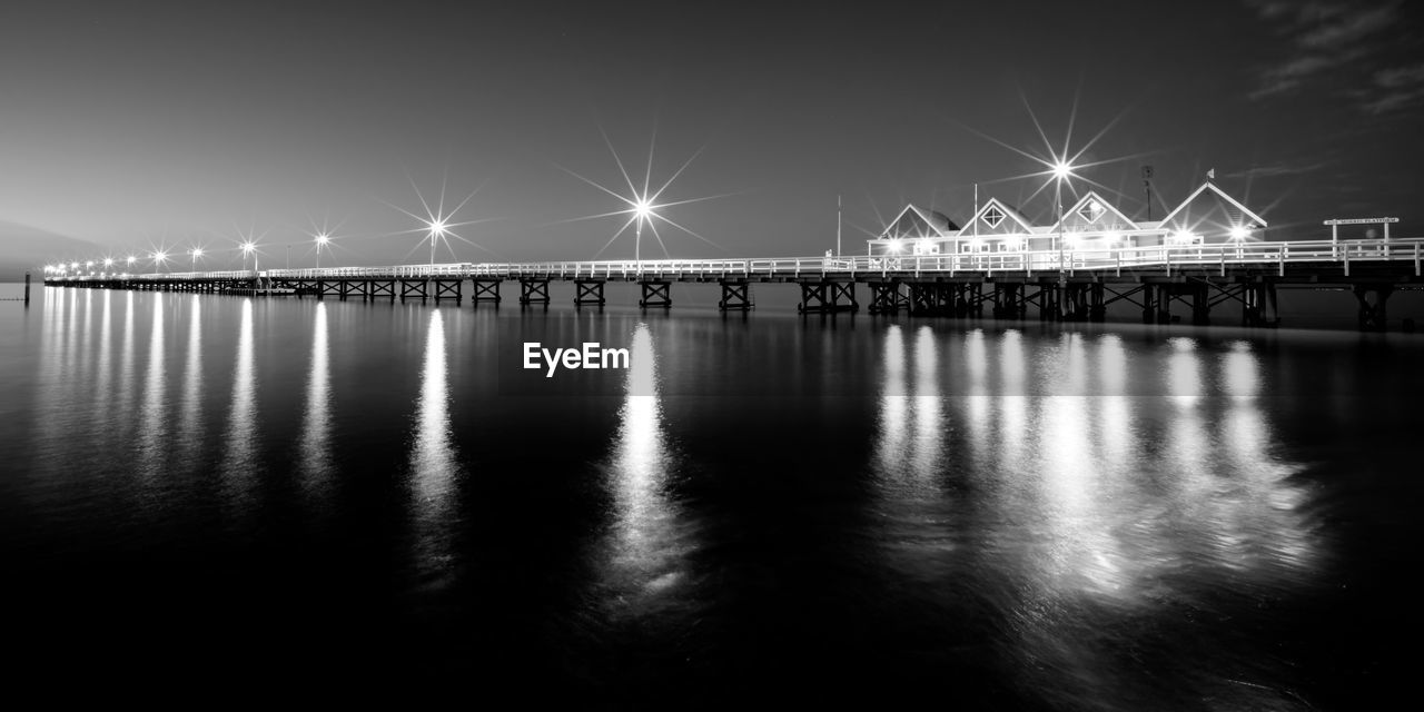 Illuminated bridge over water at night