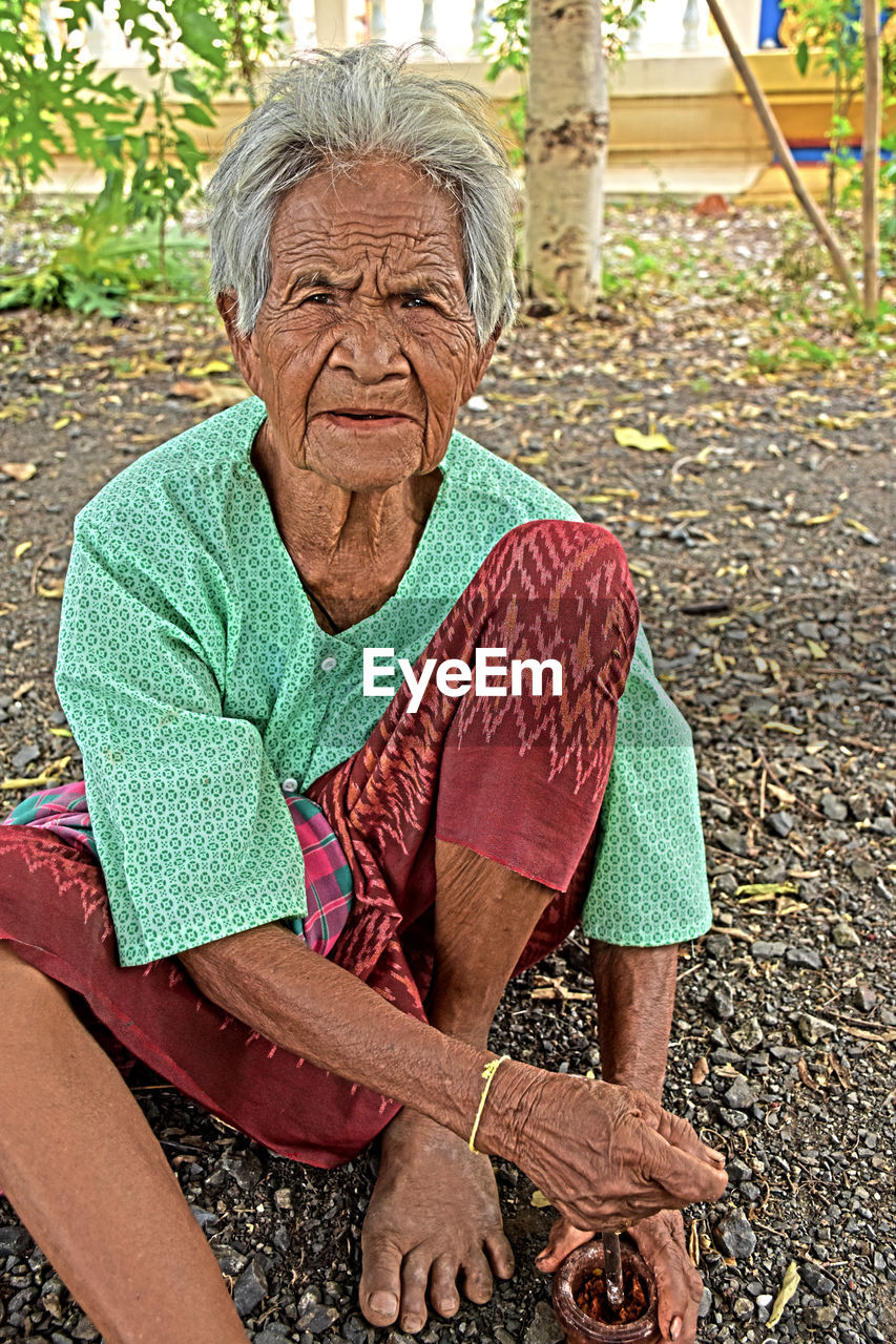 Portrait of senior woman sitting on land