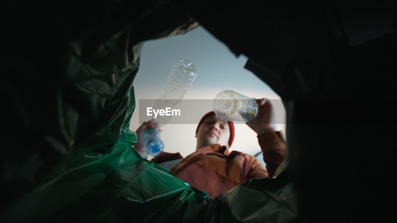 Man throwing a plastic bottle into a trash bin. bottom view from the trash bin. eco concept 