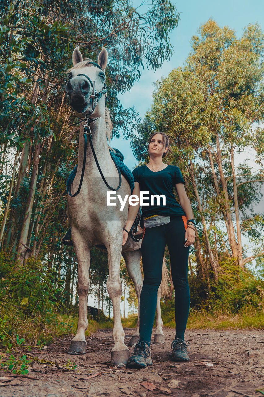 Young woman standing with horse against sky