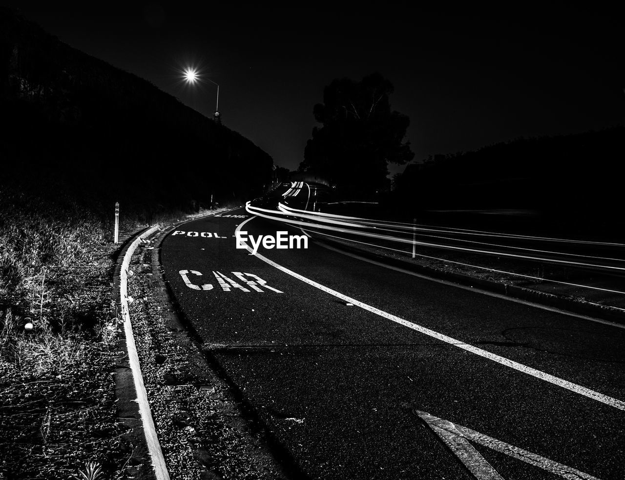 Empty road along illuminated street lights at night