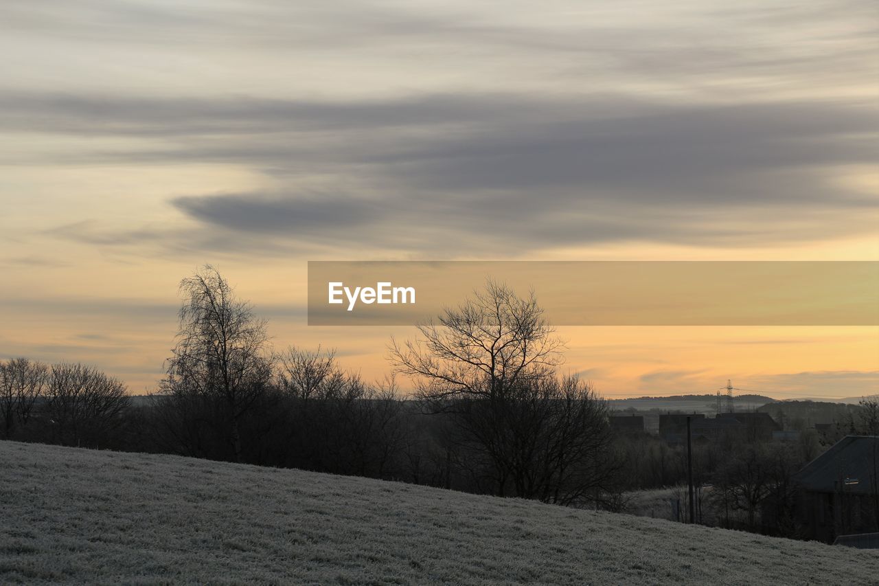 Scenic view of frozen landscape against cloudy sky during sunset