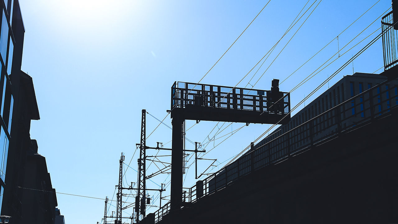 Low angle view of electricity pylons against building