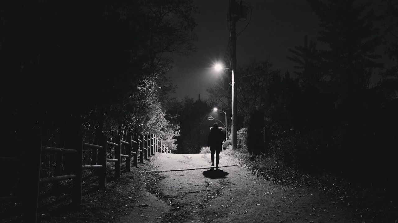 MAN WALKING ON ILLUMINATED STREET LIGHT