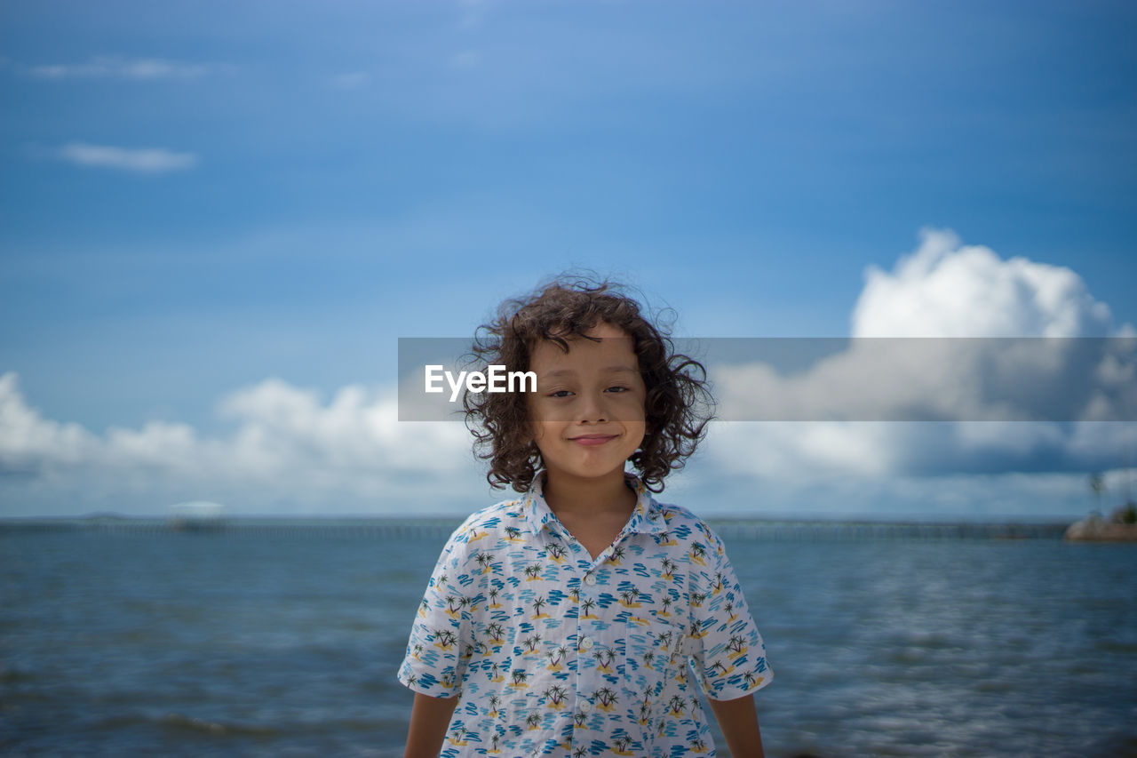 Portrait of a boy standing against sea against sky