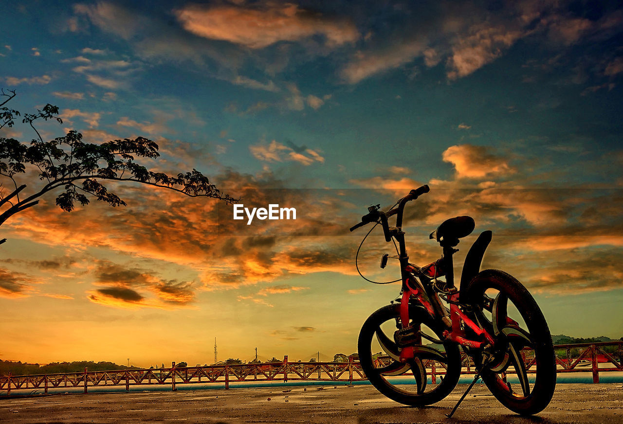 SILHOUETTE BICYCLE ON BEACH AGAINST ORANGE SKY