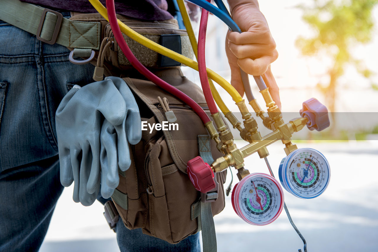 Midsection of technician holding gauge