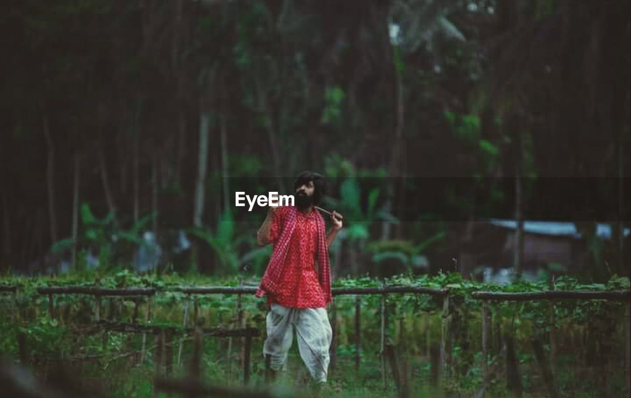 WOMAN STANDING BY PLANTS IN FOREST