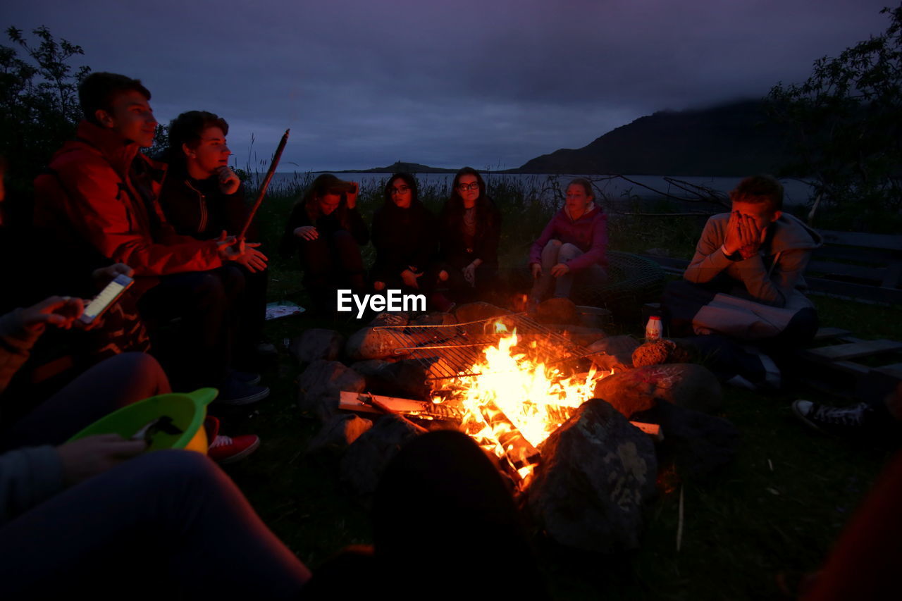 PEOPLE ON BARBECUE GRILL AGAINST SKY