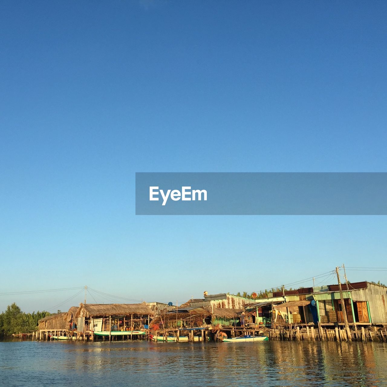 BUILDINGS BY LAKE AGAINST BLUE SKY