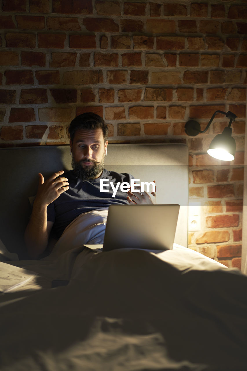 Businessman using laptop on bed at night