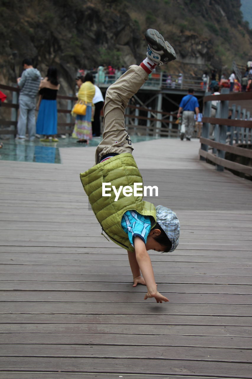 Side view of girl performing handstand on wooden bridge