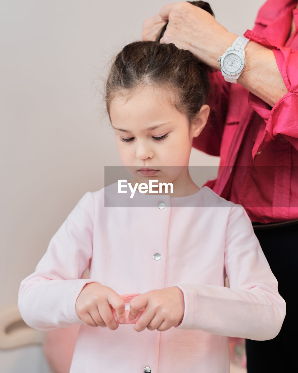 Expressive little girl being dressed by grandmother