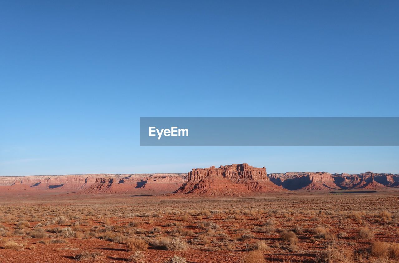 Scenic view of desert against clear blue sky